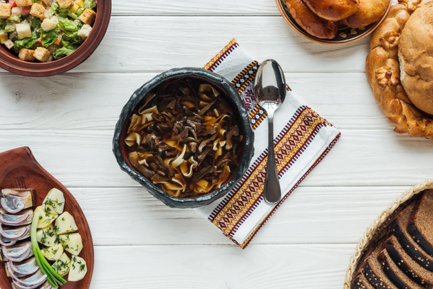 pyszne tradycyjne zupa grzybowa z haftowany ręcznik, łyżka i dania całego na białym tle drewnianych - Zdjęcie, obraz