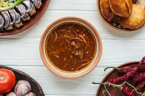 vista dall'alto di gustosa zuppa di carne mista tradizionale e piatti intorno su sfondo di legno bianco
 - Foto, immagini