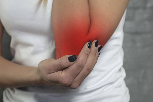 woman shows that her elbow hurts, red colour - 写真・画像