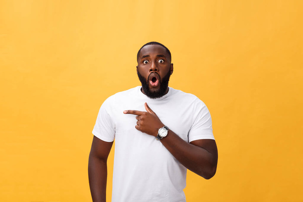 Verbaasd jonge African American hipster dragen witte t-shirt bedrijf handen in verrast gebaar, houden van mond wijd open, op zoek geschokt - Foto, afbeelding