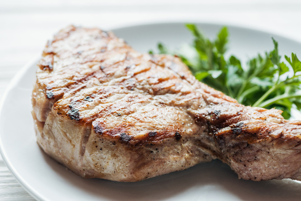 gros plan de délicieux steak de viande de côtelette dans une assiette avec du persil
  - Photo, image