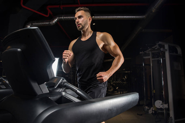 Muscular bodybuilder guy doing exercises with dumbbells in gym - Foto, imagen