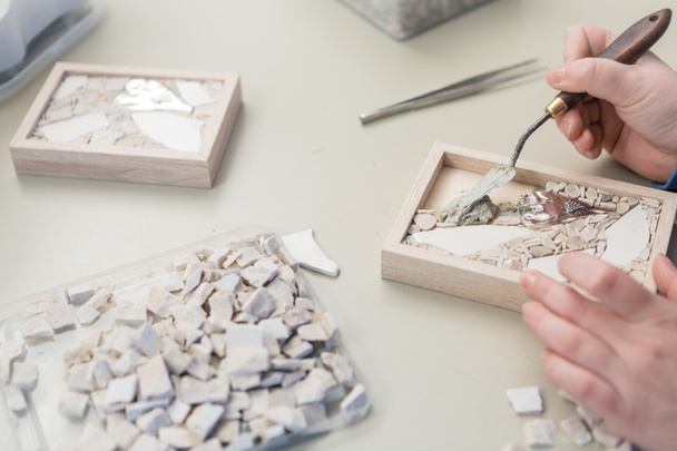 Hände der Künstlerin, die in ihrer Werkstatt an kleinen Steinmosaiken arbeiten - hautnah - Foto, Bild