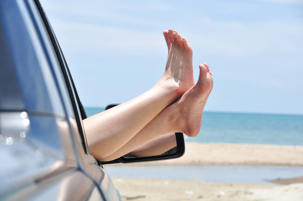 道路旅行休暇コンセプトカー。車の窓から女性の足 - 写真・画像