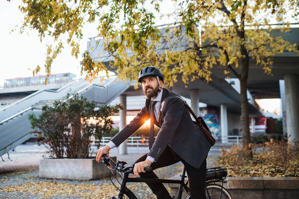 Хіпстерський бізнесмен комп'ютер з електричним велосипедом, який подорожує додому з роботи в місті на заході сонця. Копіювати простір
. - Фото, зображення