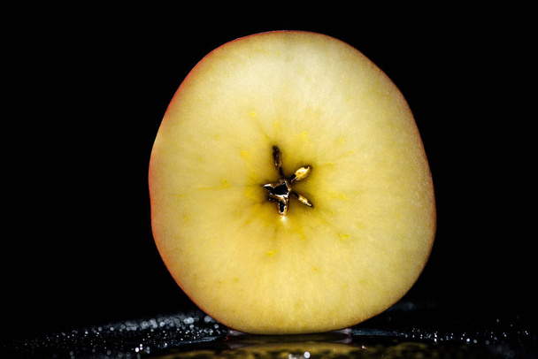 mitad de manzana madura sobre fondo negro
 - Foto, imagen