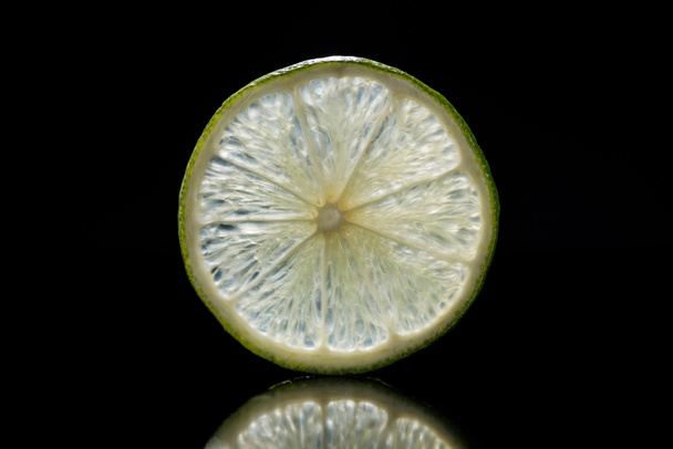 slice of fresh ripe lime isolated on black - Foto, afbeelding