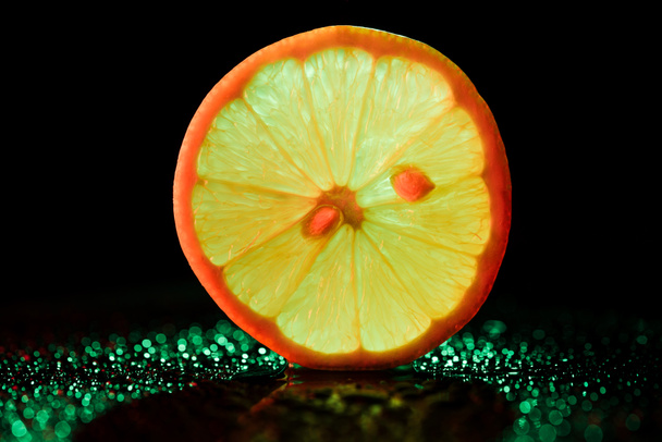 slice of lemon with neon backlit on black background - Zdjęcie, obraz