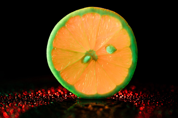 slice of neon lemon with bokeh on black background - Fotó, kép