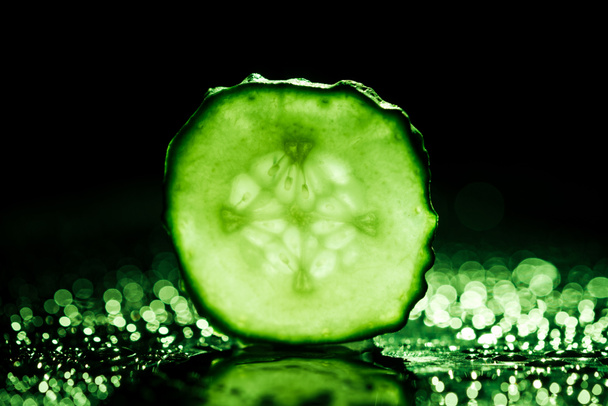 slice of cucumber with green back light on black background  - Фото, зображення