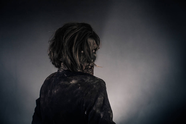 Scary zombie man posing against dark background - Фото, изображение