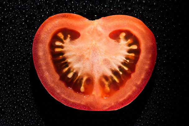 ломтик свежего помидора с капельками воды на черном фоне
 - Фото, изображение