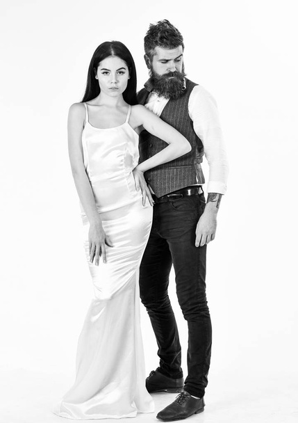 Couple in love, bride and groom in elegant clothes, white background. Bearded hipster with attractive bride dressed up for wedding ceremony. Wedding concept. Woman in wedding dress and man in vest - 写真・画像