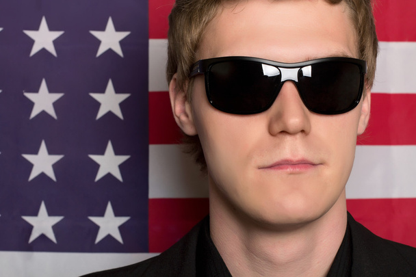 Man in sunglasses on a background of the American flag. - Photo, Image