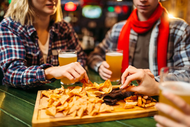 Gli appassionati di calcio bevono birra e mangiano patatine fritte a tavola nel bar dello sport. Celebrazione della vittoria, trasmissione TV, giovani amici svaghi in pub
 - Foto, immagini