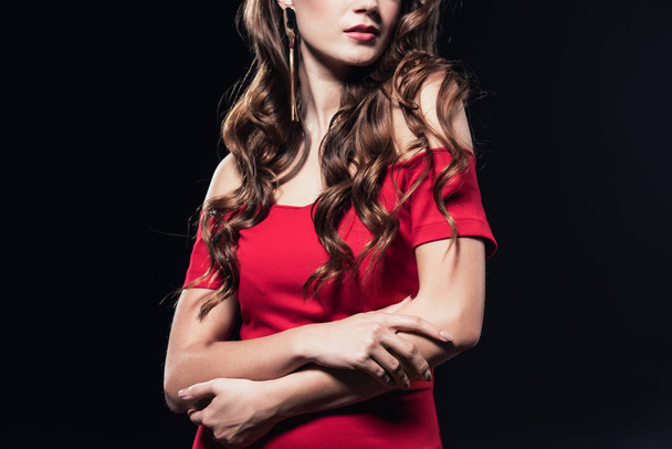 cropped view of woman in red dress posing with arms crossed isolated on black - Photo, Image