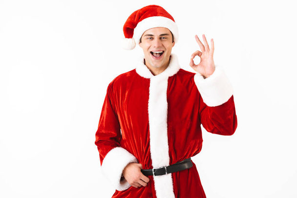 Portrait of caucasian man 30s in santa claus costume and red hat gesturing with smile isolated over white background in studio - Photo, Image