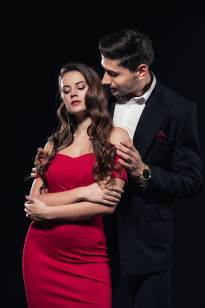 man embracing woman in red dress isolated on black - Фото, изображение