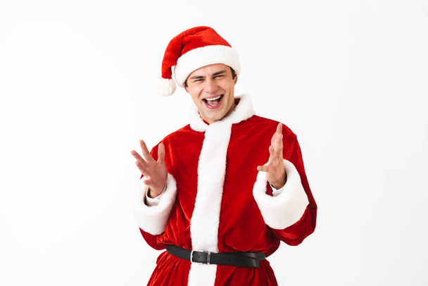 Portrait of happy man 30s in santa claus costume and red hat laughing isolated over white background in studio - Foto, immagini