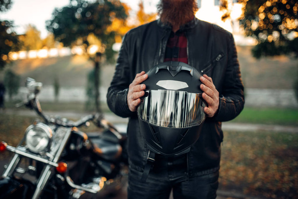 motociclista masculino segura capacete nas mãos, helicóptero clássico no fundo. Bicicleta vintage, ciclista de estrada e sua motocicleta, estilo de vida liberdade, ciclismo
 - Foto, Imagem