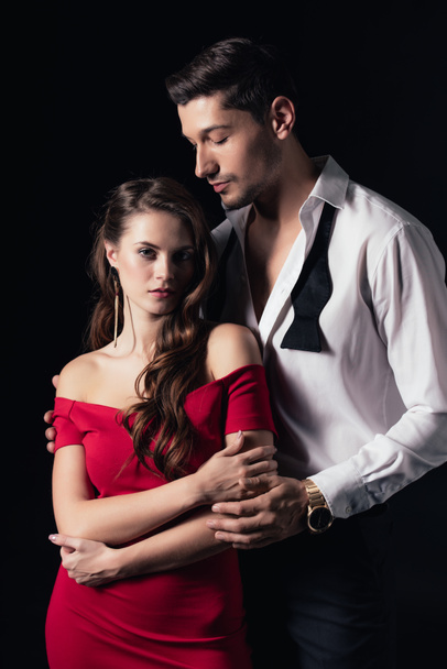 beautiful young romantic couple in formal wear hugging isolated on black - Zdjęcie, obraz