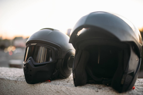 Two biker helmets with sunglasses and visor on concrete parapet closeup view, nobody, biking concept - Photo, Image