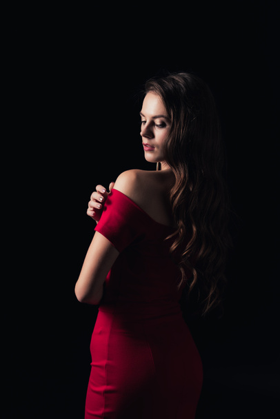 atractiva mujer en vestido rojo con los ojos cerrados posando aislado en negro
 - Foto, Imagen