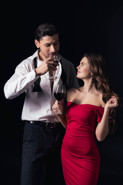 beautiful smiling couple drinking red wine isolated on black - Foto, imagen