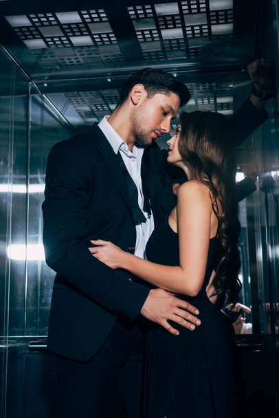 beautiful romantic couple passionately looking at each other and embracing in elevator - Photo, Image