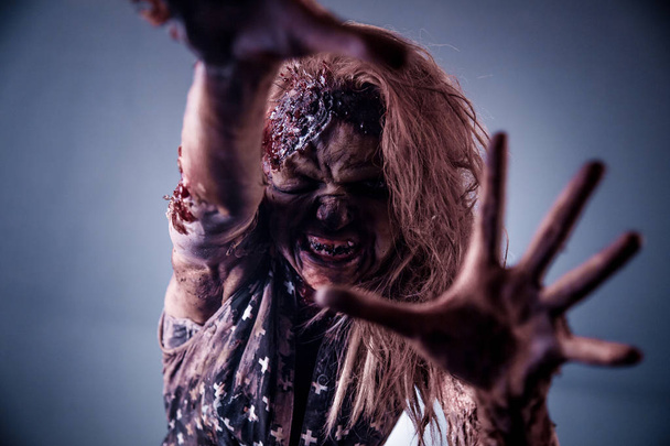 Scary zombie woman posing against dark misty background - Фото, изображение