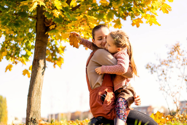 mother and daughter playing in the autumn park - Foto, afbeelding