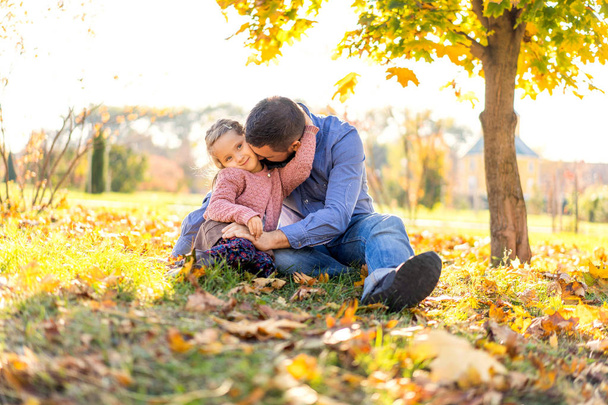 onnellinen isä tyttärensä kanssa auringonlaskun aikaan kävelemässä puistossa syksyllä
 - Valokuva, kuva