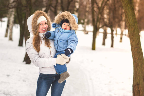 Happy young mother walking with her baby in the park in winter - Photo, Image