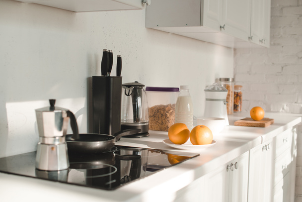 zon in witte keuken met serviesgoed en vruchten - Foto, afbeelding