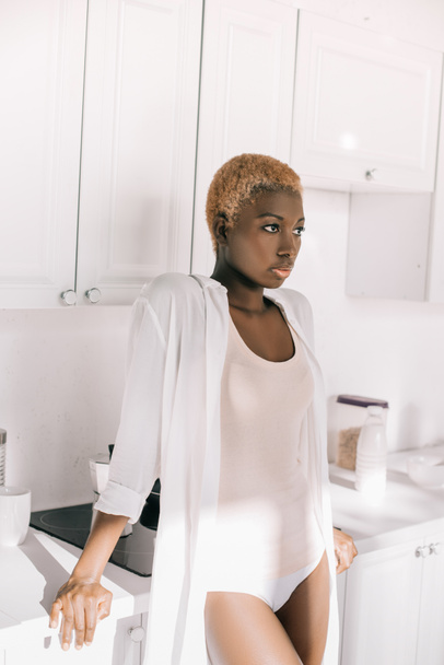 mujer afroamericana con pelo corto en pijama en cocina blanca
 - Foto, Imagen