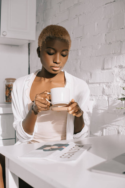 attractive african american woman holding cup in white kitchen  - Foto, Imagen