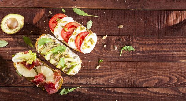 Collection of three diferent kinds of bruschetta on wooden table background. - Fotoğraf, Görsel