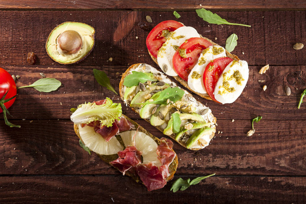 Collection of three diferent kinds of bruschetta on wooden table background. - Foto, afbeelding