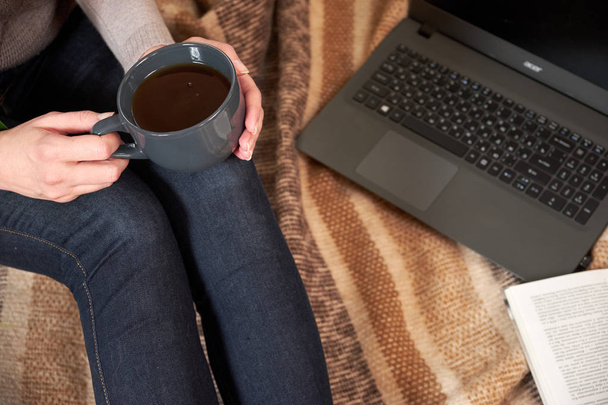 woman with a Cup of tea, a book, a laptop on a blanket - Fotó, kép