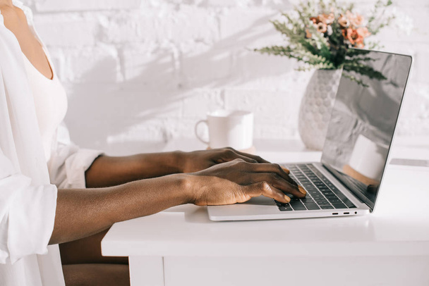 cropped view of african american woman using laptop in white kitchen  - Foto, Imagem