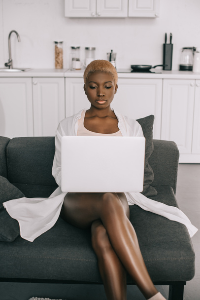 beautiful african american woman typing on laptop in living room  - 写真・画像