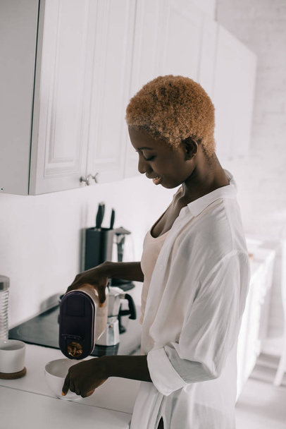 Beyaz mutfakta kahvaltı hazırlarken mutlu Afrikalı-Amerikalı kadın  - Fotoğraf, Görsel