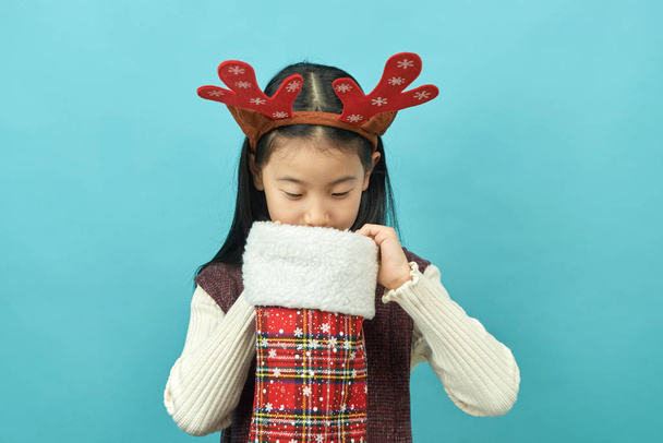 クリスマス コンセプトの頭飾りとアジアの女の子子は分離された青の背景にかわいいアジア女の子のクローズ アップ. - 写真・画像