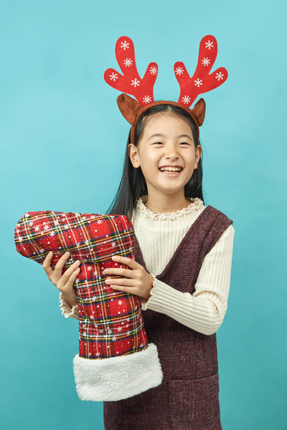 Asiatique fille avec un Noël concept headdress enfant, Gros plan de mignon petite fille asiatique sur fond bleu isolé
. - Photo, image