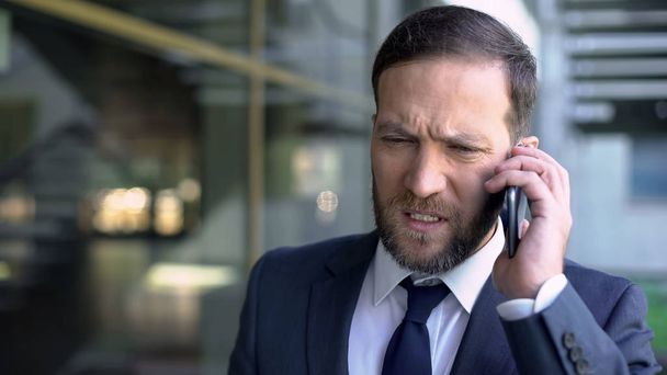 Worried businessman talking on phone, finding out about his bankruptcy, problems - Фото, изображение