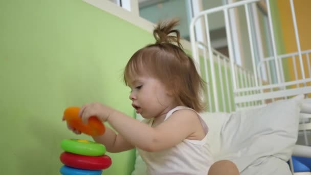 Çocuk çocuk ve bebek yatakta bir piramit ve renkli halkalar ile oynamak. Anaokulu ve kreş çocuklar için eğitici oyuncaklar. Oyuncak kız. - Video, Çekim