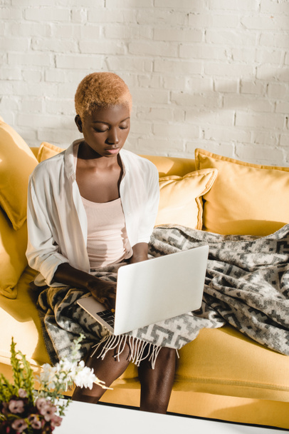 concentrated african american woman typing on laptop in living room  - Foto, Bild