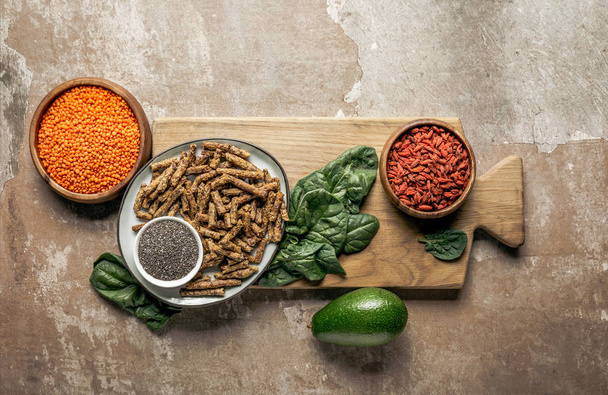 vista superior de granola saudável, bagas de goji, lentilhas vermelhas e espinafre na placa de madeira com fundo rústico
 - Foto, Imagem