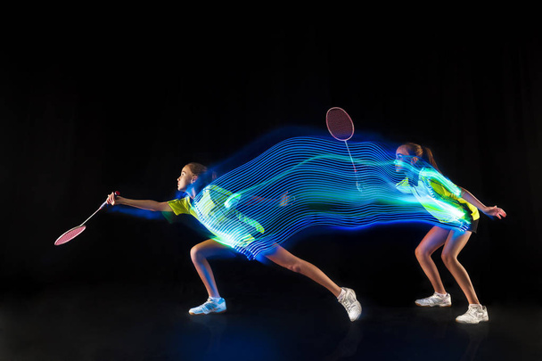one caucasian young teenager girl woman playing Badminton player on black background - Foto, Bild