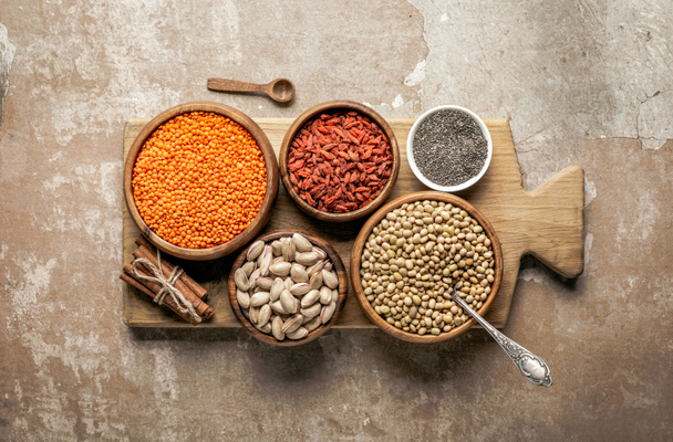 top view of wooden board with legumes, goji berries and healthy ingredients with rustic background - Photo, Image